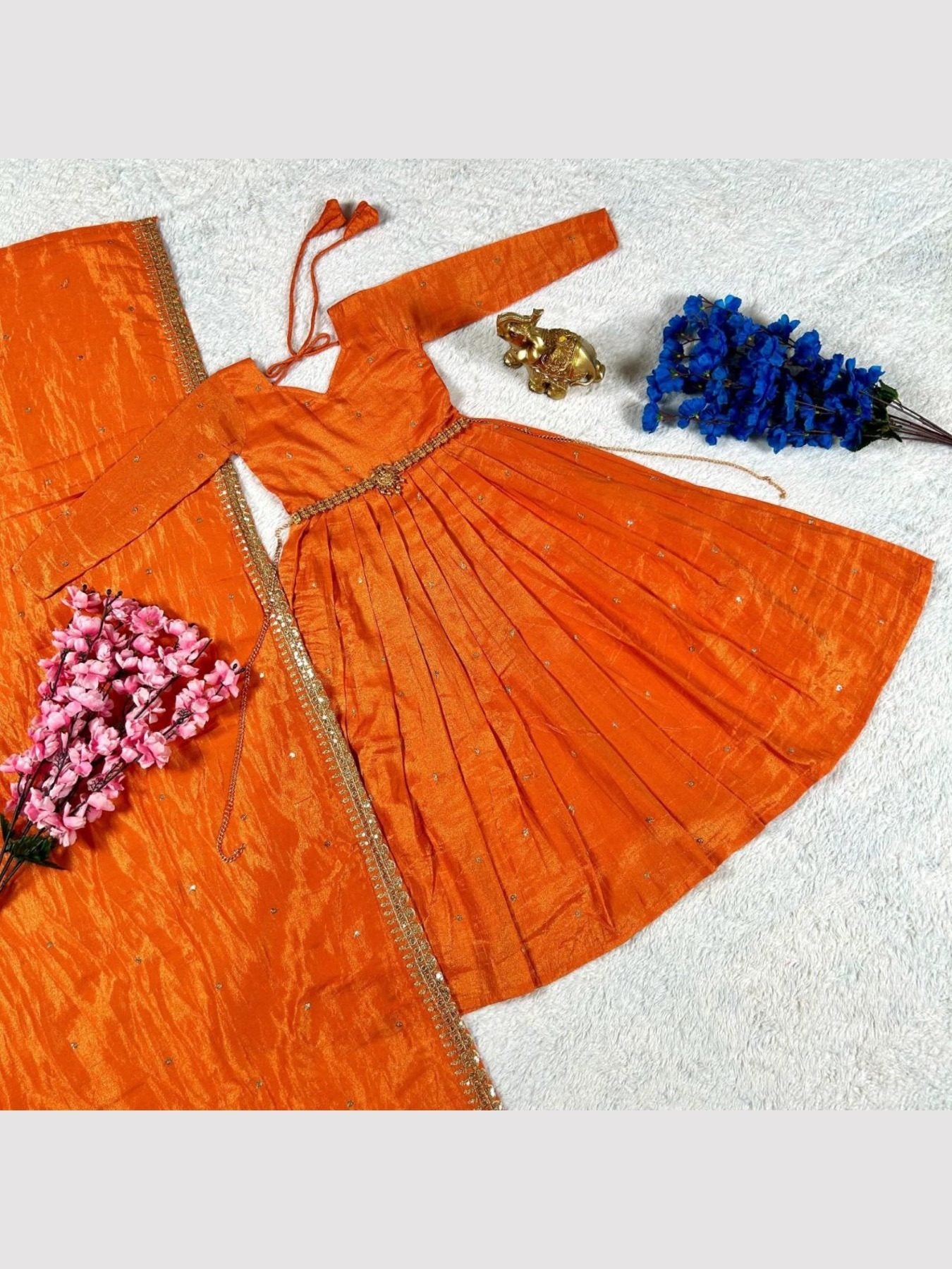 Orange silk gown with dupatta laid out, floral decor