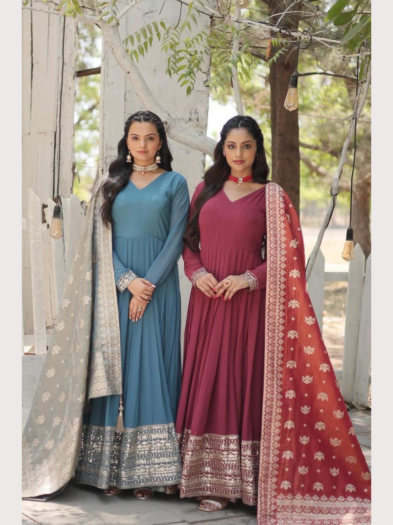 Two women in blue and maroon embroidered gowns with dupattas