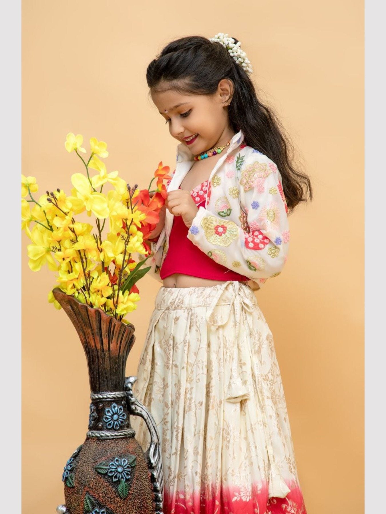 Girl in floral jacket and lehenga admiring flowers