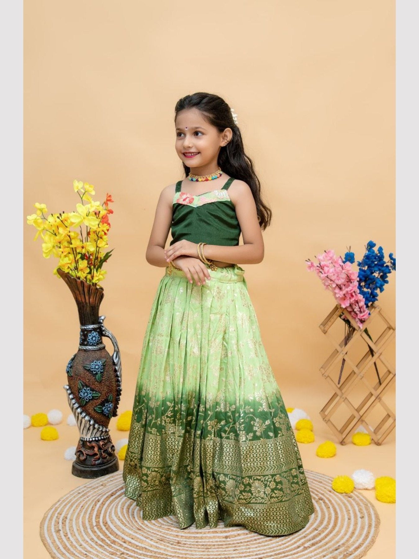 Girl wearing green lehenga choli, floral backdrop